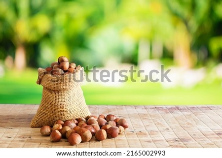 Hazelnuts, filbert in burlap sack and in brown bowl on  wooden table. heap or stack of hazelnuts. in front of the background of trees
 Royalty-Free Stock Photo #2165002993