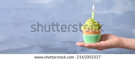 Woman holding birthday cupcake on light blue background, closeup view with space for text. Banner design