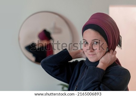 Religious Jewish woman puts a shawl on her head in front of a mirror. Back view (21) Royalty-Free Stock Photo #2165006893
