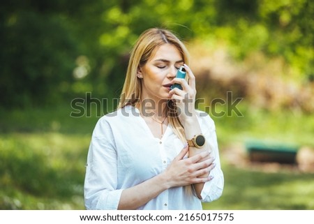 An asthmatic girl who takes an inhaler and has an asthma attack. A young woman has an asthma attack. She's holding an inhaler. She walks outside and has a problem with asthma Royalty-Free Stock Photo #2165017575