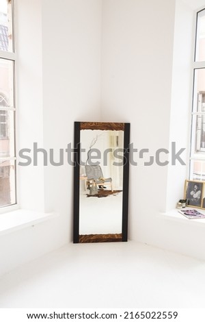 a wooden-framed mirror in a white room. a mirror in a white room. mirror in a wooden frame