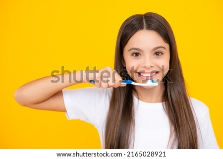 Happy teenager portrait. Teenager girl brushing her teeth over isolated yellow background. Daily hygiene teen child hold toothbrush, morning routine. Dental health oral care. Smiling girl. Royalty-Free Stock Photo #2165028921