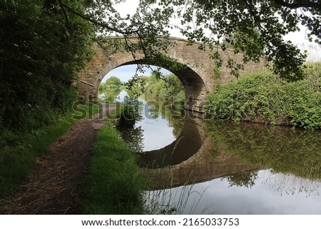 A beautiful landscape shot of a bridge over the Leeds-Liverpool canal. The reflection of the bridge can be seen in the water below. 
