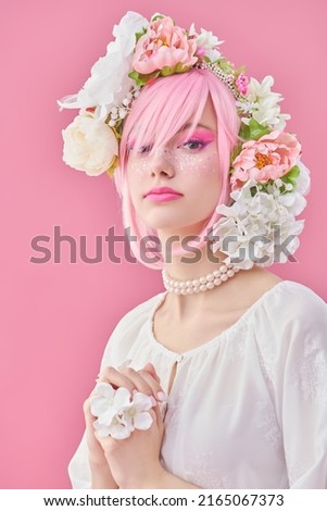 Spring and summer beauty. A lovely girl with bright pink makeup and pink hair with floral wreath on her head. Japanese anime style. Pink background. Beauty girl. 