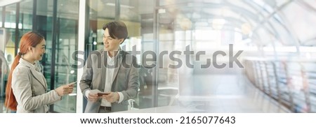 Young business man and woman at check-in counter with airlines staff. Airline transportation and tourism concept, Image panorama for cover design.