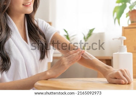 Healthy skin care, beauty asian young woman in bathrobe, towel after shower bath at home, hand in applying, putting moisturizer on her arm. Skin body cream moisturizing lotion, routine in the morning Royalty-Free Stock Photo #2165092973
