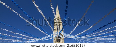 Notre Dame church tower in Bergerac with plastic flower decorations. Royalty-Free Stock Photo #216510187