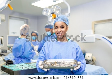 Female surgeon in surgical uniform taking surgical instruments at operating room. Young woman doctor in hospital operation theater