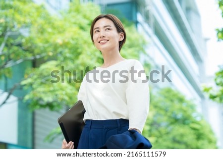 A smiling woman standing in the office district Royalty-Free Stock Photo #2165111579