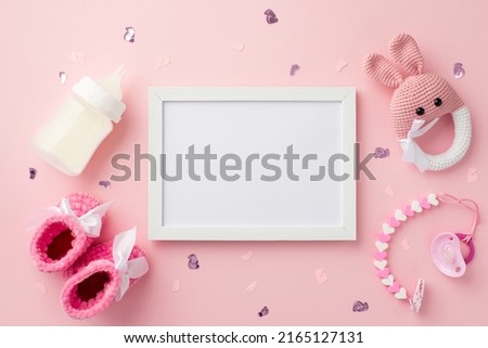 Baby accessories concept. Top view photo of white frame pink booties pacifier chain bottle knitted bunny rattle toy and confetti on isolated pastel pink background with empty space