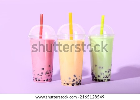Plastic cups of tasty bubble tea on purple background