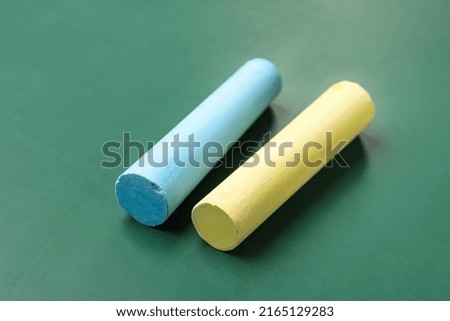 Blue and yellow chalks on green blackboard