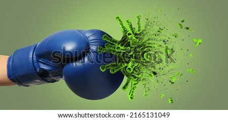 Hand in boxing glove kicking cigarette on green background. Concept of immunity Royalty-Free Stock Photo #2165131049