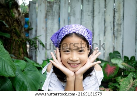 Potriat of adorable little asian girl on white shirt smiling with garden background.