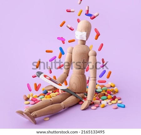 Many falling pills and wooden human mannequin with thermometer on lilac background