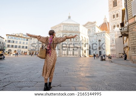Woman enjoys beautiful view on famous Duomo cathedral in Florence, standing on empty cathedral square during morning time. Stylish woman visiting italian landmarks. Traveling Italy concept Royalty-Free Stock Photo #2165144995