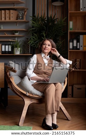 business woman in a beige suit working at the office, typing on computer