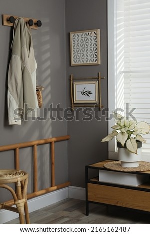 Stylish hallway interior with bamboo frame on grey wall