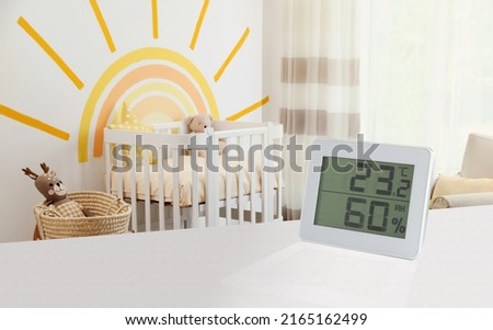 Digital hygrometer with thermometer on white table in children's room. Optimal humidity level for kids Royalty-Free Stock Photo #2165162499