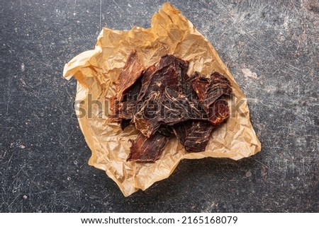 Beef jerky meat. Dried sliced meat on a paper. Top view.