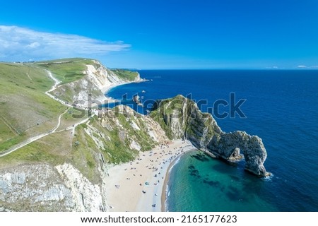 The drone aerial view of Durdle Door and beach. Durdle Door is a natural limestone arch on the Jurassic Coast near Lulworth in Dorset, England. Royalty-Free Stock Photo #2165177623