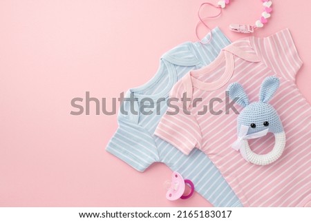 Baby accessories concept. Top view photo of pink and blue infant clothes pacifier chain and knitted bunny rattle toy on isolated pastel pink background