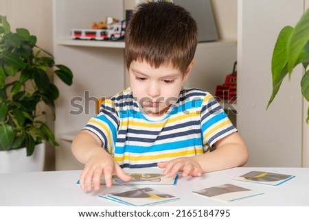 A 4-year-old boy puts together a picture of a raccoon from puzzles while sitting at the table
