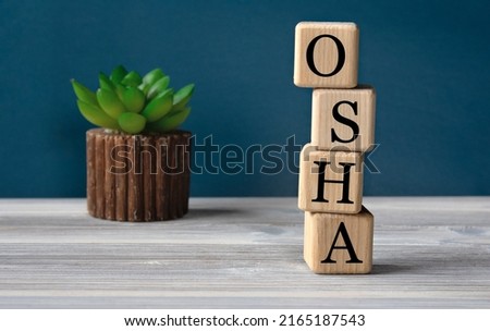 OSHA (Occupational Safety and Health Administration) - acronym on wooden cubes on the background of a cactus. Busines concept Royalty-Free Stock Photo #2165187543