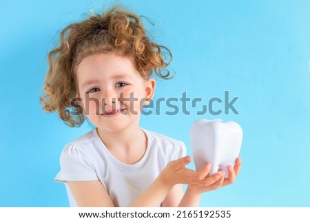 Little cute smiling girl holding tooth dent in hand. Kid training oral hygiene. creative medical dentistry . Child learning brushing, cleaning teeth. Prevention of caries in children. dental care kids Royalty-Free Stock Photo #2165192535