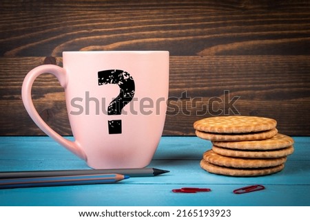 Question mark on a pink coffee mug. Blue and black wooden background.