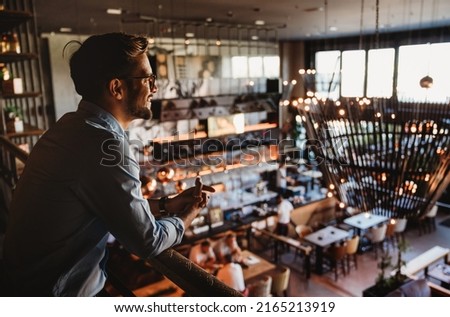 Happy businessman, restaurant owner proudly looking at crowded restaurant Royalty-Free Stock Photo #2165213919