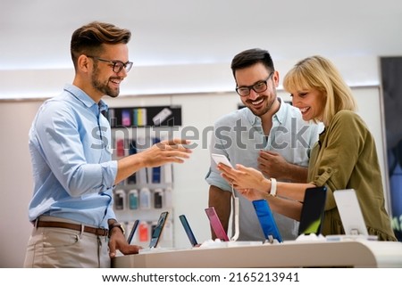Portrait of salesman helping to people to buy a new digital device in tech shop Royalty-Free Stock Photo #2165213941