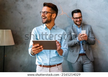 Young smiling successful business man, entrepreneur in formal business suite working on tablet