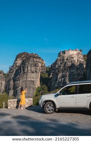 woman near suv car taking picture of meteora monastery at thessaly mountains greece