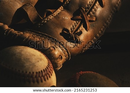Golden light on old vintage baseball glove with ball close up for history of traditional sport. Royalty-Free Stock Photo #2165231253