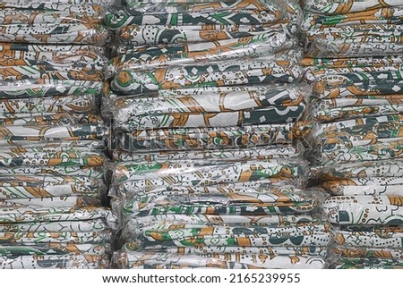 a pile of batik cloth, predominantly green, neatly arranged on a warehouse shelf. Royalty-Free Stock Photo #2165239955