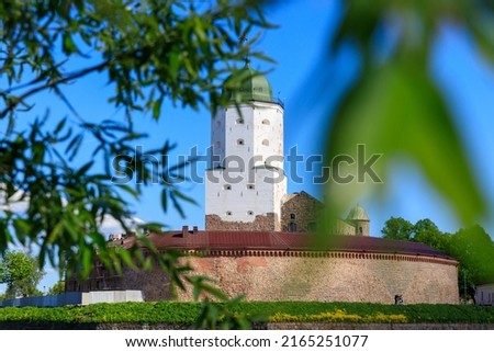 Medieval fortress in Vyborg. Castle on the water against the blue sky with green foliage