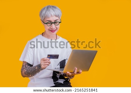 old senior asian woman tattoo hand show credit card laptop with smile confident and cheerful studio shot,asia old woman grey hair standing hand gesture hold credit care cashless payment business ideas