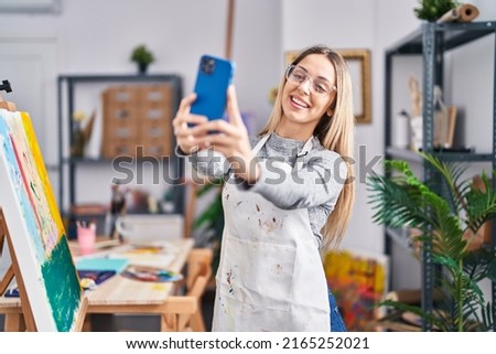 Young woman artist smiling confident making selfie by the smartphone at art studio