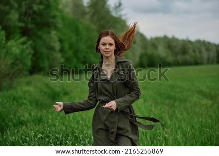 a beautiful, happy woman runs across a green field with flowing red hair. Emotions of happiness. High quality photo