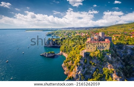 Impressive summer view from flying drone of Duino Castle. Fantastic morning scene of Adriatic coast of Italy, Europe. Beautiful cityscape of Duino town. Traveling concept background.