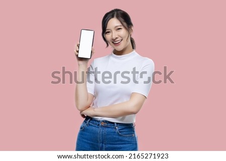 Happy young Asian woman feeling happiness and gesture showing mobile smartphone blank screen on isolated pink background.