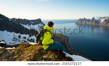 Man traveler sitting on cliff mountain travel vacations in Norway enjoying landscape adventure lifestyle outdoor activity Senja islands. Artistic picture. Beauty world. The feeling of complete freedom