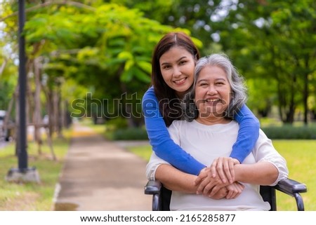 Asian careful caregiver or nurse taking care of the patient in a wheelchair.  Concept of happy retirement with care from a caregiver and Savings and senior health insurance, a Happy family Royalty-Free Stock Photo #2165285877