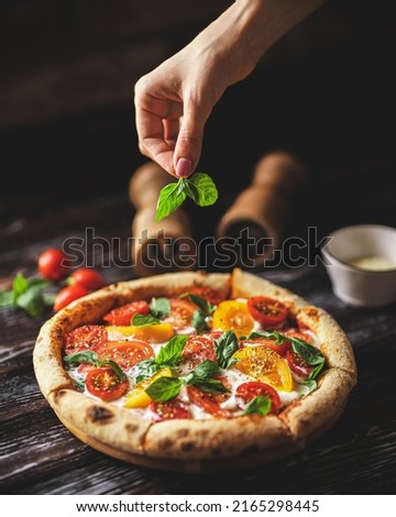 Appetizing pizza with tomatoes and cheese on a dark wooden background. Slice of pizza with stretchy cheese Royalty-Free Stock Photo #2165298445