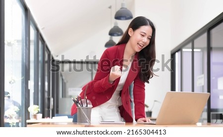 Excited happy woman looking at the phone screen, celebrating an online win, overjoyed young asian female screaming with joy at office