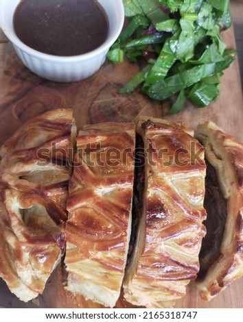 Jakarta June 2022, beef wellington with back pepper sauce and vegetables, plating in a wooden plate with bokeh picture 