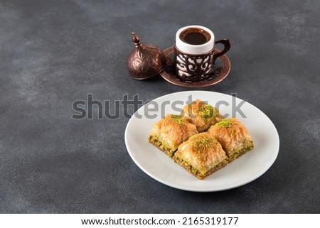 Traditional pistachio baklava with Turkish coffee.A plate of baklava on dark background Royalty-Free Stock Photo #2165319177