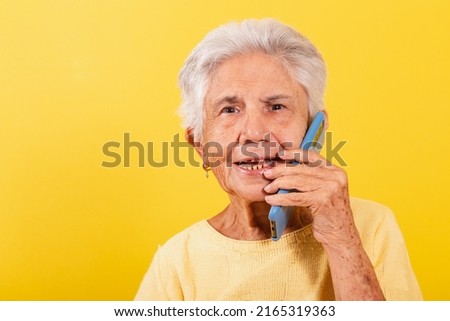 Old lady, holding cell phone, inclusion of the elderly in the digital environment, online, smartphone. Talking by voice call.