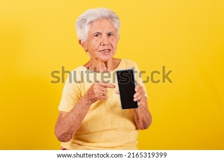 Old lady, holding cell phone, inclusion of the elderly in the digital environment, online, smartphone. Pointing to screen.